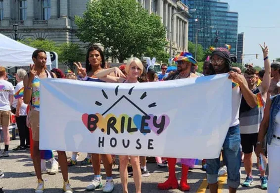 The B. Riley House community marching with its banner at a Pride parade